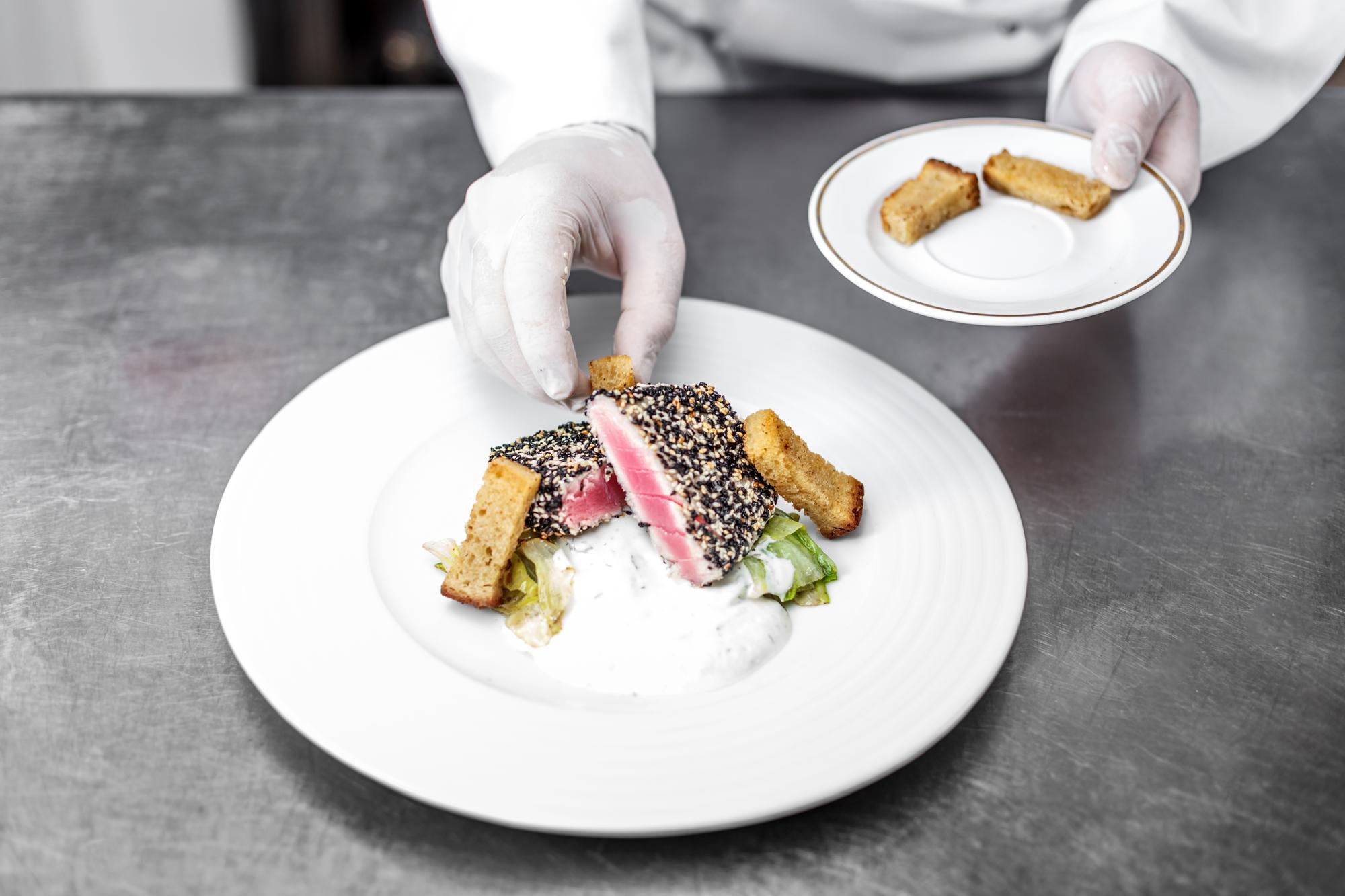Chef handing a plated course to guest in modern setting